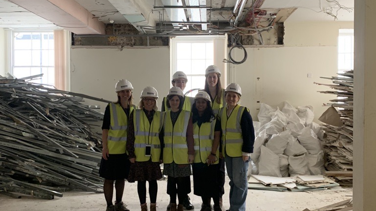 An image of seven people in hard hats in a building site