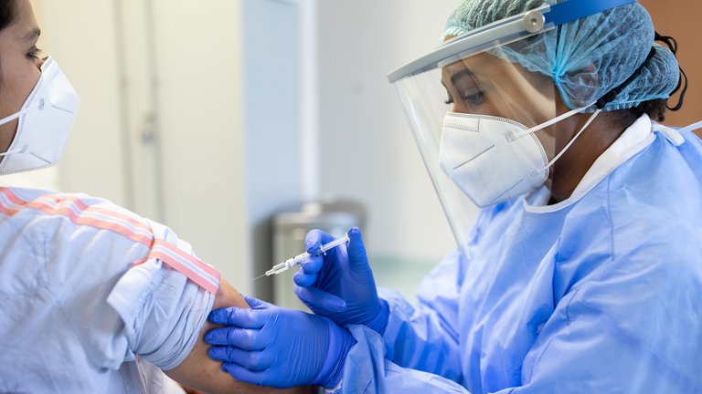 A doctor or nurse vaccinating a patient with a syringe
