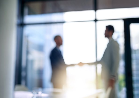 A blurred image of an introductory handshake between two figures at a job interview