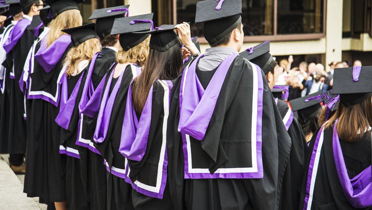 A group of students at a graduation ceremony wearing black and purple robes