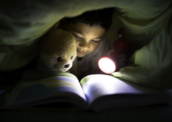 A boy reading a book in bed