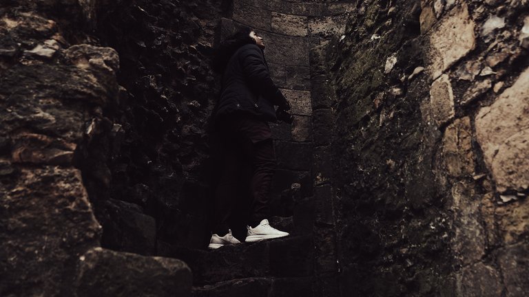Man ascends the steps of a ruined stone tower