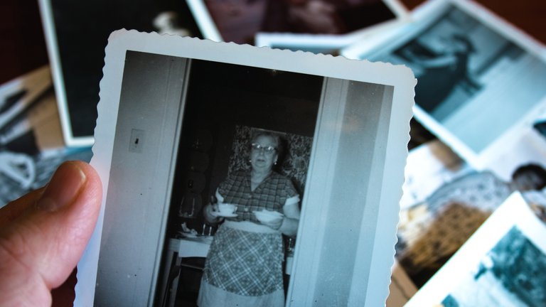 Hand holds black and white photograph of a woman serving soup