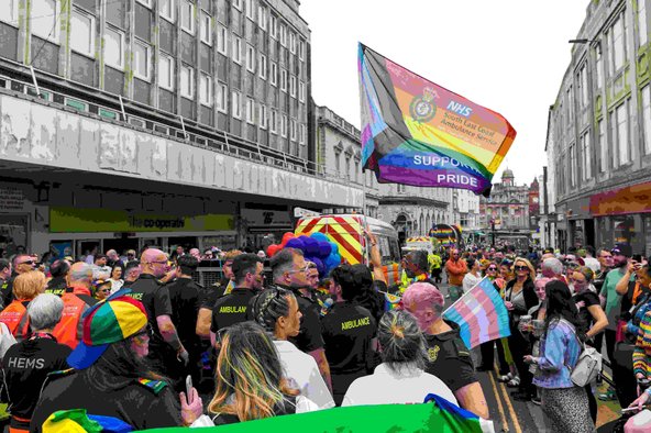 Members of the South East Coast Ambulance Service with a large rainbow banner taking part in the Brighton Pride 2024 parade
