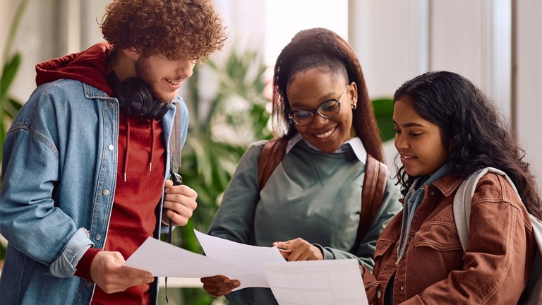3 Students looking at their results together and smiling