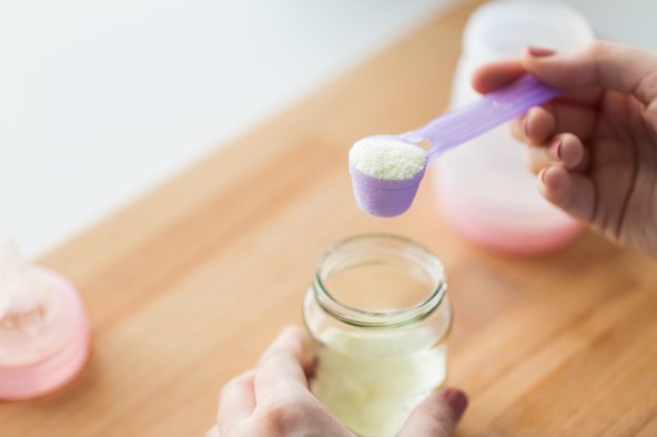 An image of a hand scooping baby formula into a baby bottle