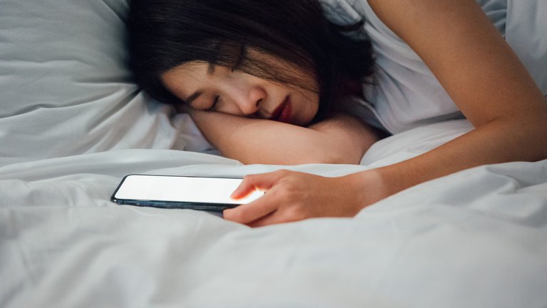 Photograph of a woman asleep next to her mobile phone
